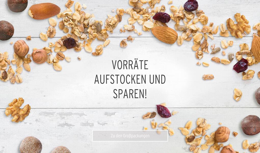 Weiße Holzoberfläche mit verstreuten Nüssen, Trockenfrüchten und Granola. Mittig steht der Text Vorräte aufstocken und sparen! in schwarzer Schrift.