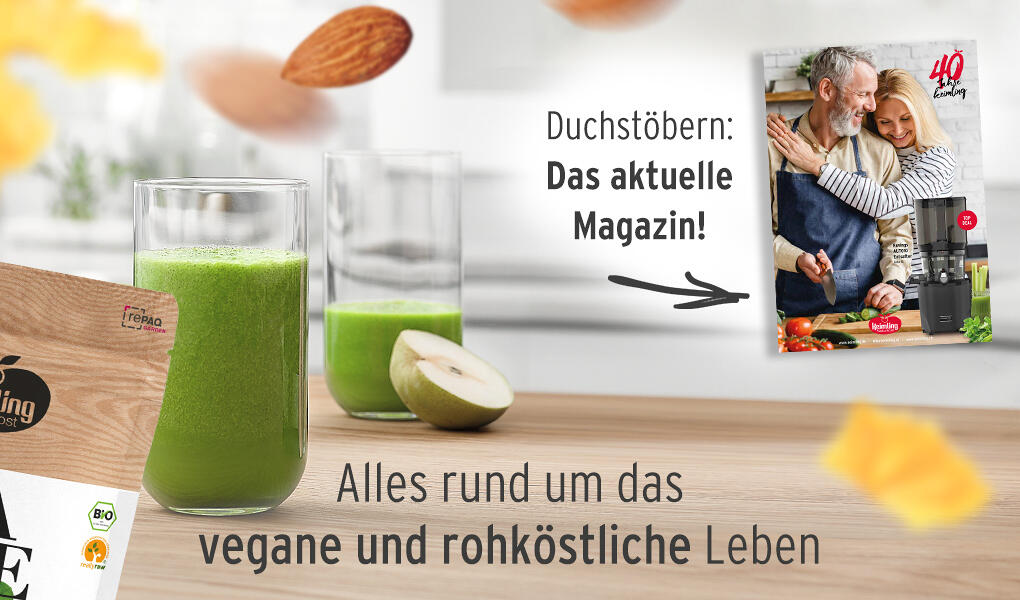 Zwei GlĂ€ser mit grĂŒnem Smoothie stehen auf einem Holzbrett, daneben eine halbierte grĂŒne Frucht. Im Hintergrund ist ein Magazin mit einem Paar in der KĂŒche und dem Text 40 Jahre Keimling.