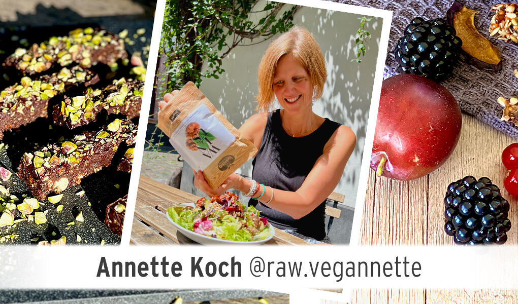 Annette Koch sitzt draußen an einem Holztisch und hält eine braune Packung mit einem weißen Aufkleber, auf dem eine orangene Pilzillustration zu sehen ist.