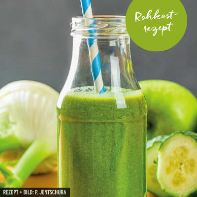 Quer-durchs-Beet-Smoothie von P. Jentschura Grüner Smoothie in einer Glasflasche mit blau-weiß gestreiftem Papierstrohhalm. Im Hintergrund sind eine halbe Gurke, ein Apfel und Fenchel zu sehen. Auf der Flasche prangt ein grüner Aufkleber mit weißer Aufschrift Rohkostrezept.