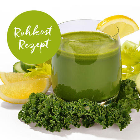 Grüner Smoothie in einem Glas mit einem Glasrand aus Zitronenscheibe. Umgeben ist das Glas von frischem Grünkohl, Zitronenscheiben und weiteren grünen Zutaten. Ein grüner Kreis zeigt den Text Rohkost Rezept.