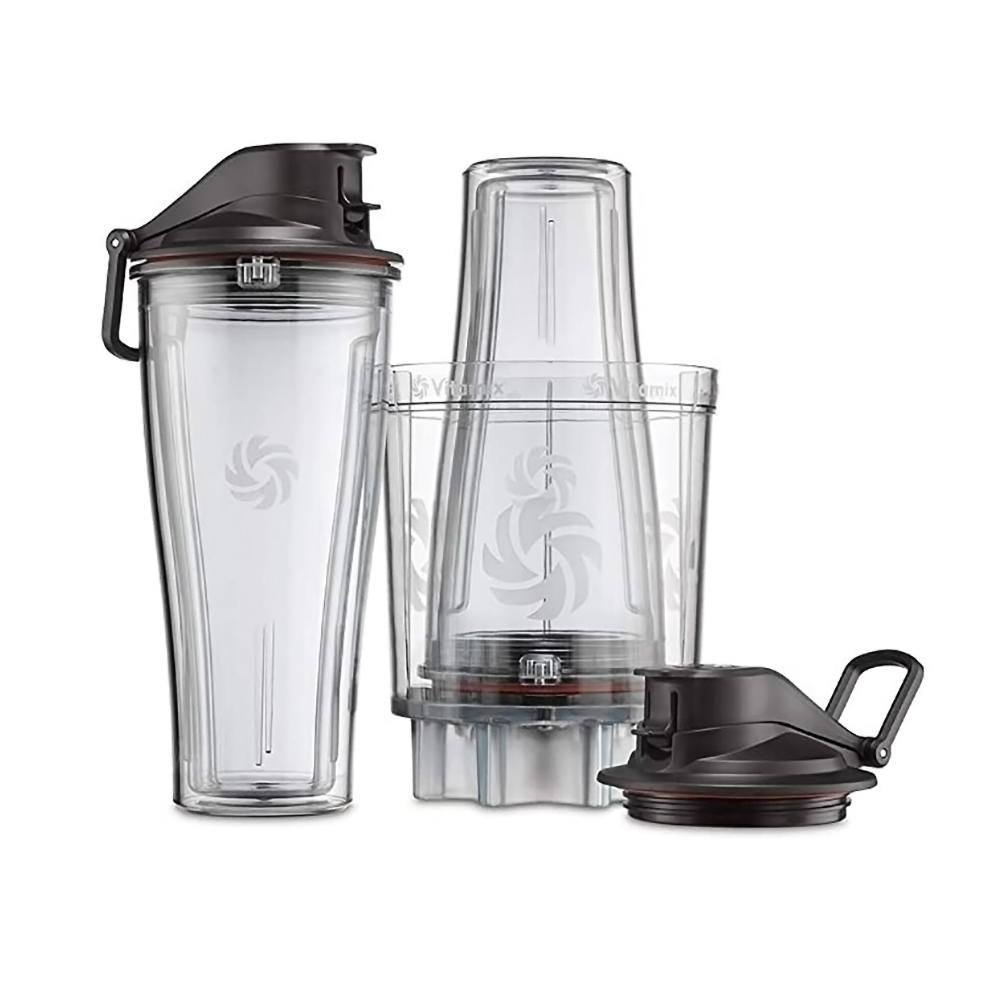Zwei transparente Vitamix Mixbehälter mit schwarzen Deckeln stehen nebeneinander. Ein Deckel liegt separat daneben. Alle Teile tragen das Vitamix-Logo.