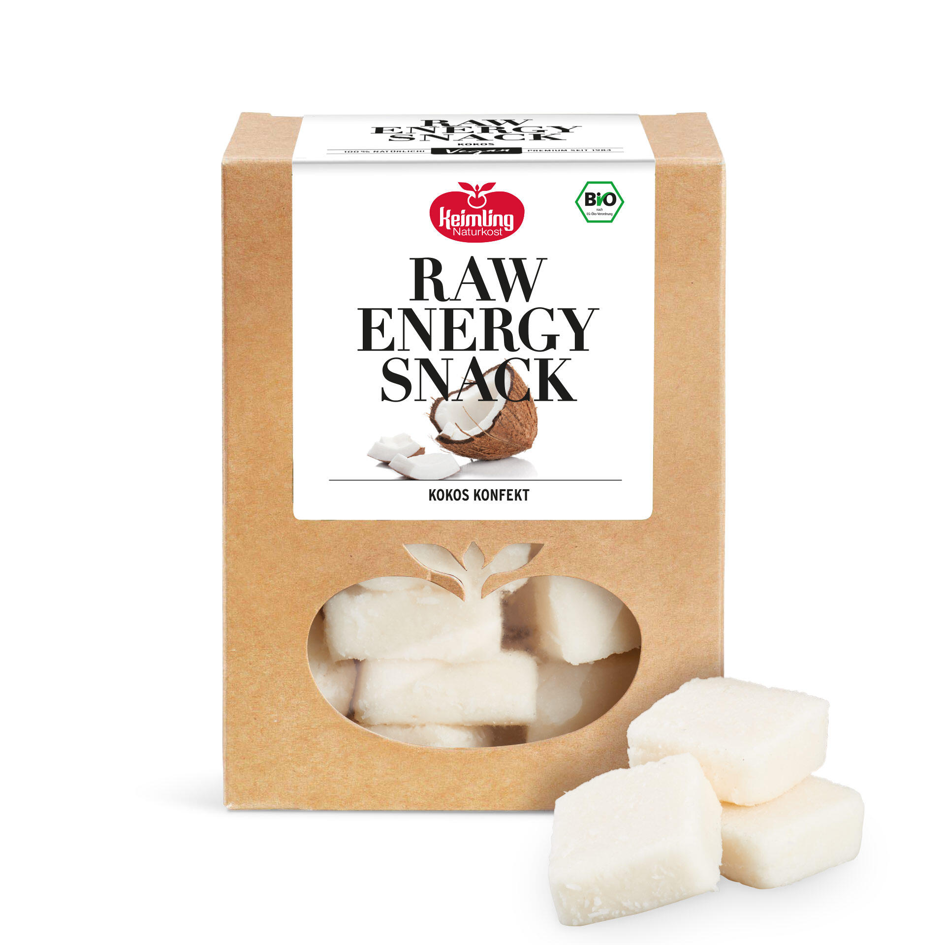 Verpackung des Keimling Naturkost Raw Energy Snack Kokos Konfekt in brauner Pappbox mit Fenster in Apfelform und drei weißen, würfelförmigen Kokos-Stücken daneben.