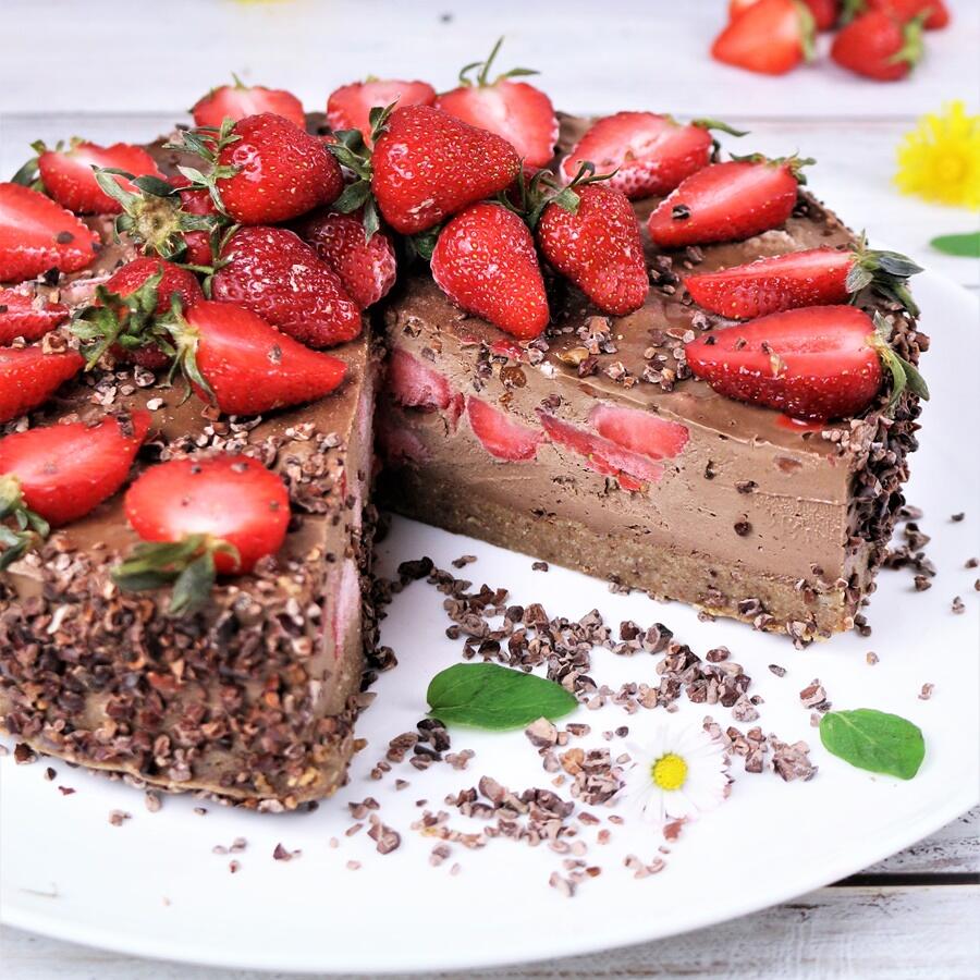 Mousse au Chocolat Torte, roh-vegan Mousse-au-Chocolat-Torte mit roher veganer Schokoladenmousse und frischen, ganzen sowie halbierten Erdbeeren dekoriert. Die Torte hat eine feste Kantenkruste mit Kakaonibs und ist auf einem weißen Teller angerichtet.