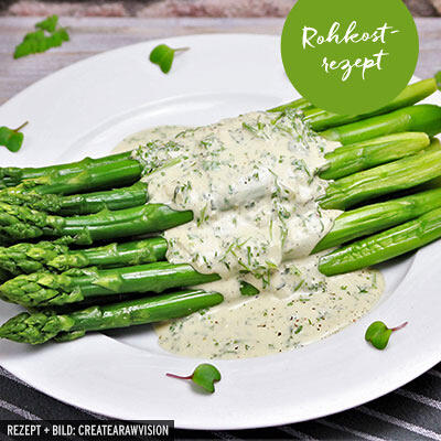 Grüner Spargel mit Sauce Bérnaise Grüner Spargel liegt auf einem weißen Teller und ist mit einer hellen Sauce Bérnaise übergossen, die feine Kräuter wie Estragon und Kerbel enthält.