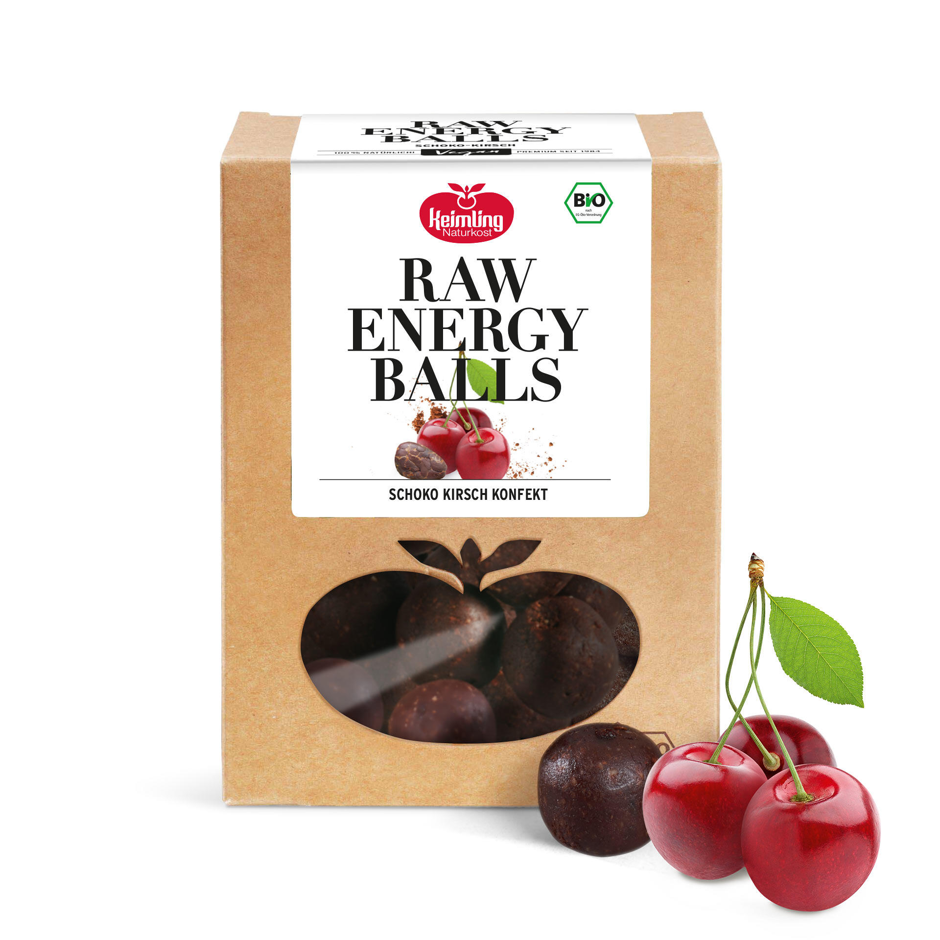 Packung Keimling Naturkost Raw Energy Balls Schoko Kirsch mit Sichtfenster, daneben drei rote Kirschen und eine Kugel des Schoko Kirsch Konfekts.