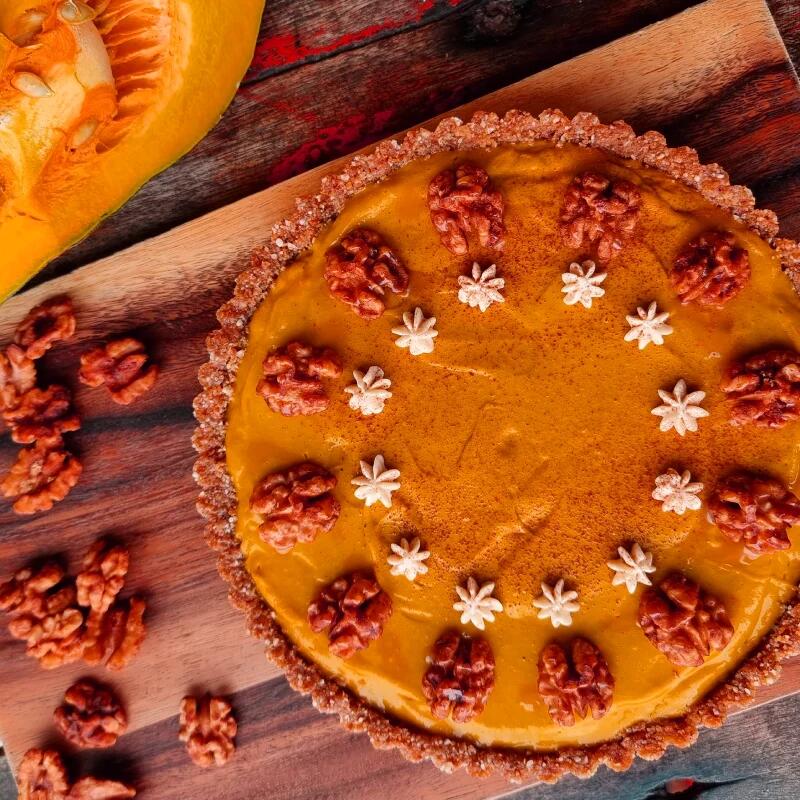 Kürbis Kuchen von Boris Lauser Herbstlicher Kürbiskuchen mit knusprigem Walnuss-Buchweizen-Boden. Die cremige Kürbisfüllung ist mit Walnusshälften und kleinen Sahneblüten garniert, leicht mit Zimt bestäubt.