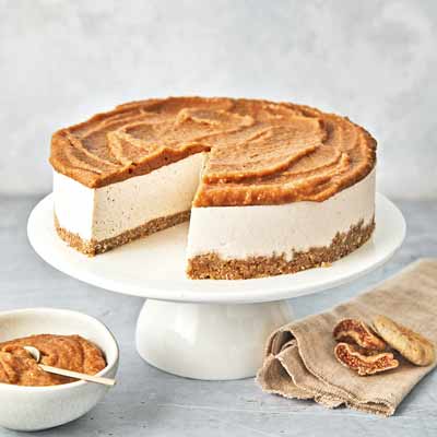 Veganer New York Cheesecake mit Feigen-Karamell Veganer New York Cheesecake mit weißer Cashew-Creme auf einem braunen Keksboden. Oben ist eine Schicht feines Feigen-Karamell in welligen Mustern verteilt. Daneben stehen eine Schale mit Feigen-Karamell und Feigen auf einem Leinentuch.