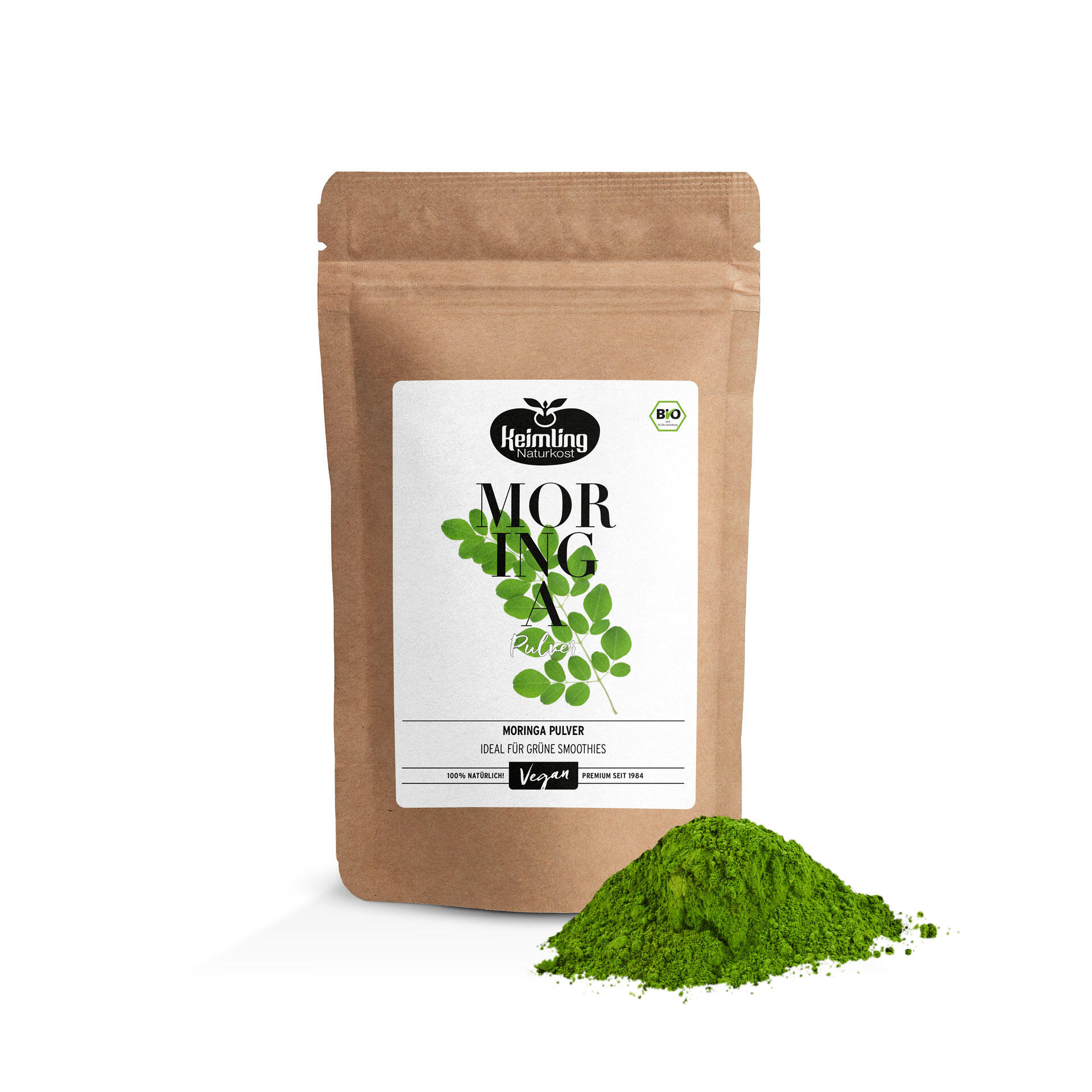 Braune Verpackung mit weißem Etikett und grünen Moringa-Blättern. Text auf dem Etikett: Kejmling Naturkost Moringa Pulver Ideal Für Grüne Smoothies Vegan 100% Natürlich Premium Seit 1984. Daneben liegt ein Häufchen grünes Pulver.