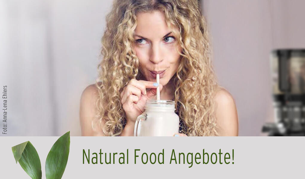Eine Frau mit langen, lockigen, blonden Haaren trinkt durch einen Strohhalm aus einem Glas mit einem hellen Getränk. Im Vordergrund steht der Text Natural Food Angebote!.