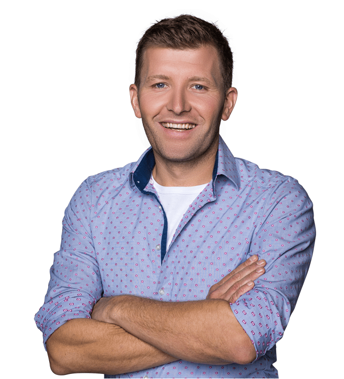 Florian Sauer steht lächelnd mit verschränkten Armen in einem hellblauen Hemd mit dezentem Muster und weißem T-Shirt.